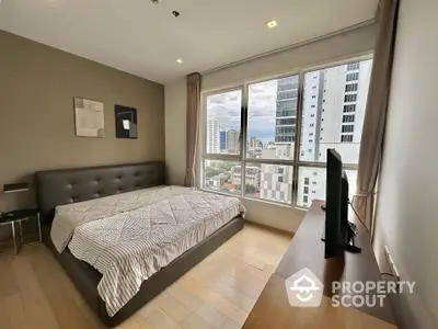 Modern bedroom with city view, featuring a large bed and sleek furniture in a high-rise apartment.