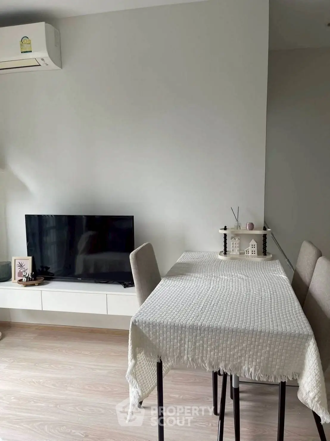 Modern dining area with sleek table, chairs, and wall-mounted TV in a cozy living space.