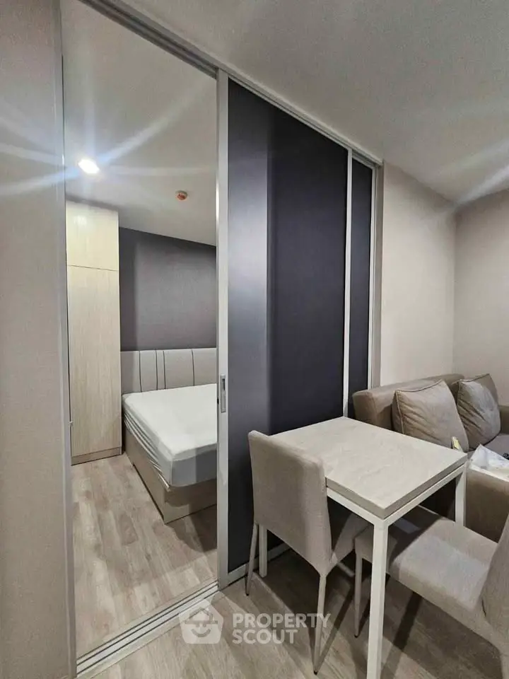 Modern apartment with cozy living area and sliding door to bedroom, featuring neutral tones and sleek furniture.