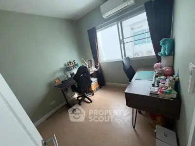 Cozy study room with desk, chair, and window view in modern apartment.