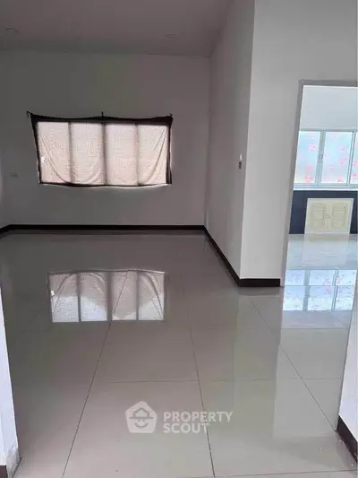 Spacious empty room with tiled flooring and large window, ready for customization.