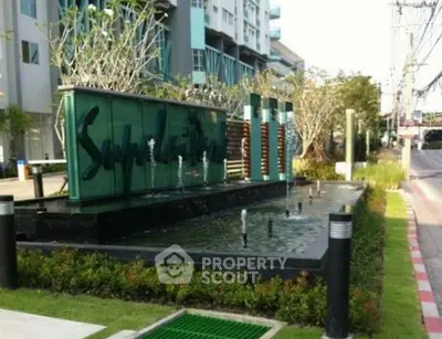 Modern building entrance with stylish water feature and lush landscaping.