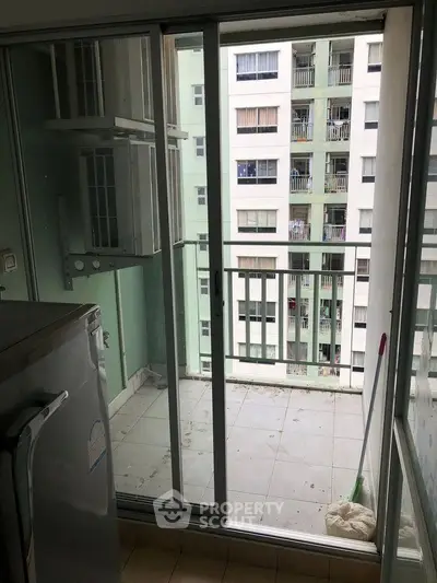 Compact balcony with sliding glass doors and view of neighboring building.