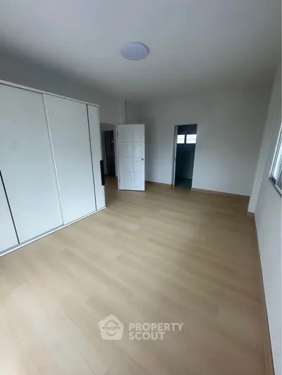 Spacious empty bedroom with wooden flooring and built-in wardrobe