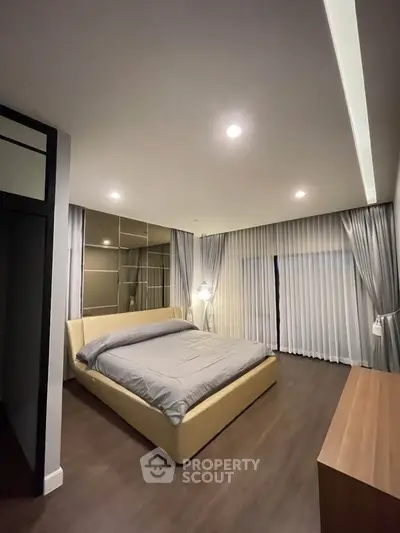 Spacious modern bedroom with elegant lighting and floor-to-ceiling curtains