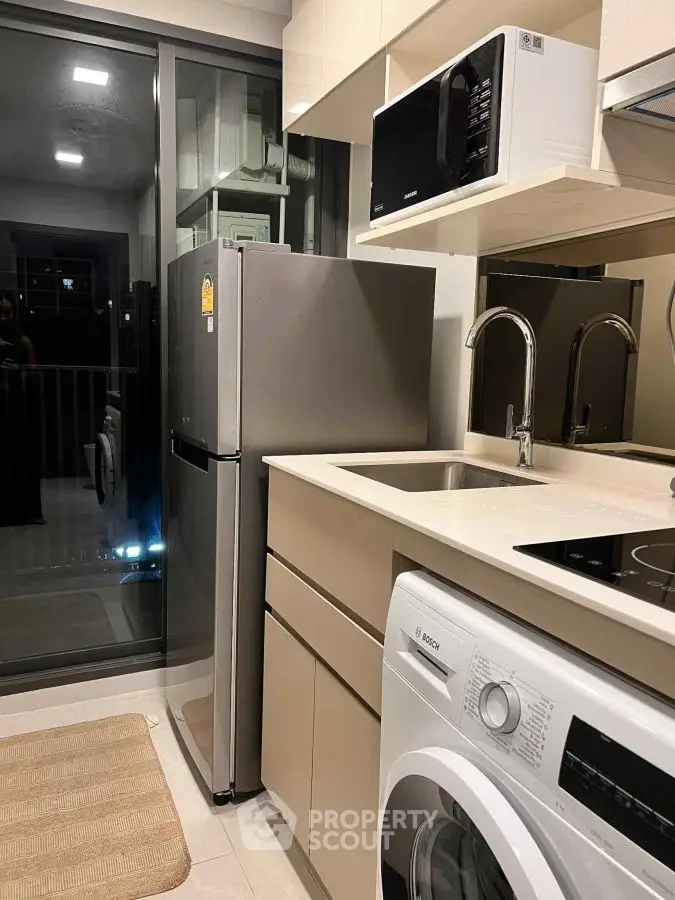 Modern kitchen with sleek appliances including fridge, microwave, and washing machine, ideal for urban living.