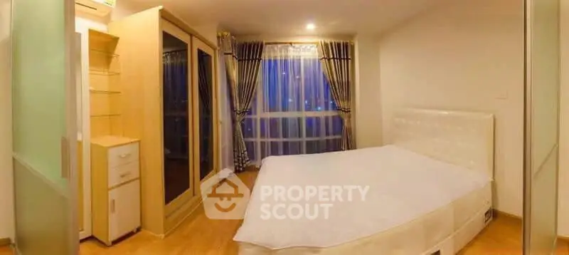 Spacious bedroom with large window and modern furnishings in a cozy apartment.