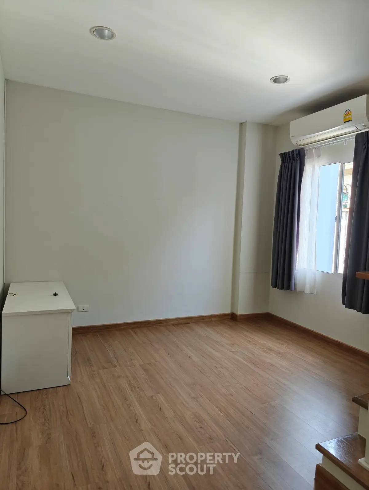 Spacious empty room with wooden flooring and natural light