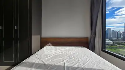 Modern bedroom with city view, featuring a large window and built-in wardrobe.