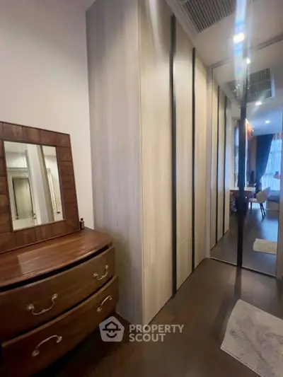 Elegant bedroom with wooden dresser and mirrored wardrobe in modern apartment.