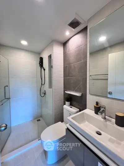 Modern bathroom with sleek design, featuring a glass shower and stylish fixtures.