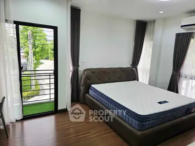Spacious bedroom with large windows and balcony access, featuring modern decor and natural light.