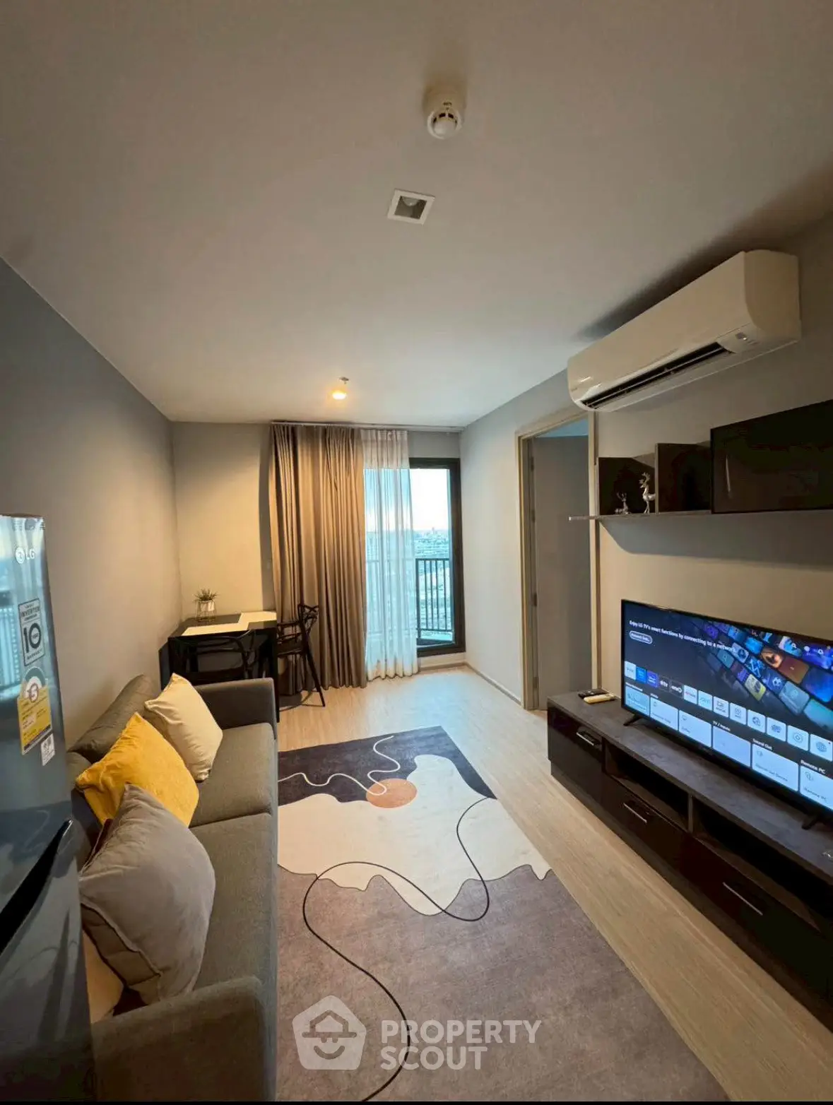 Modern living room with stylish decor and large TV, featuring a cozy sofa and air conditioning.