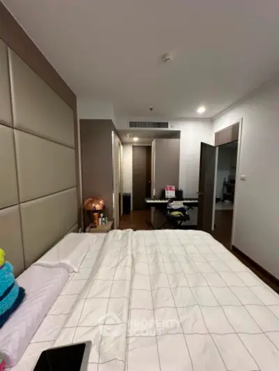 Spacious bedroom with large built-in wardrobe and warm lighting, leading to a cozy hallway and additional rooms, perfect for comfortable living.