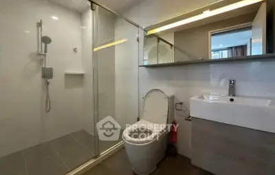Modern bathroom with glass shower and sleek fixtures in contemporary apartment.