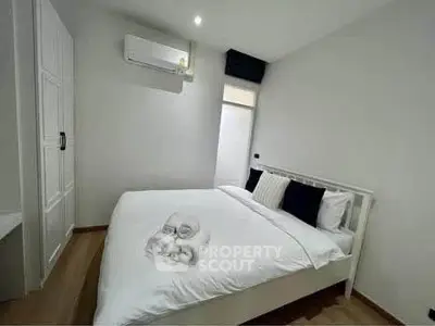 Modern bedroom with minimalist design and air conditioning, featuring a cozy bed and ample storage space.
