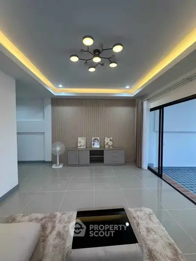 Modern living room with stylish lighting and sliding glass doors to balcony