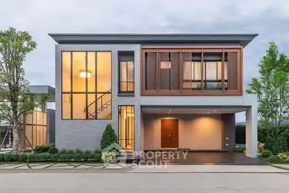 Modern two-story house with large windows and stylish facade, surrounded by lush greenery and a spacious driveway.