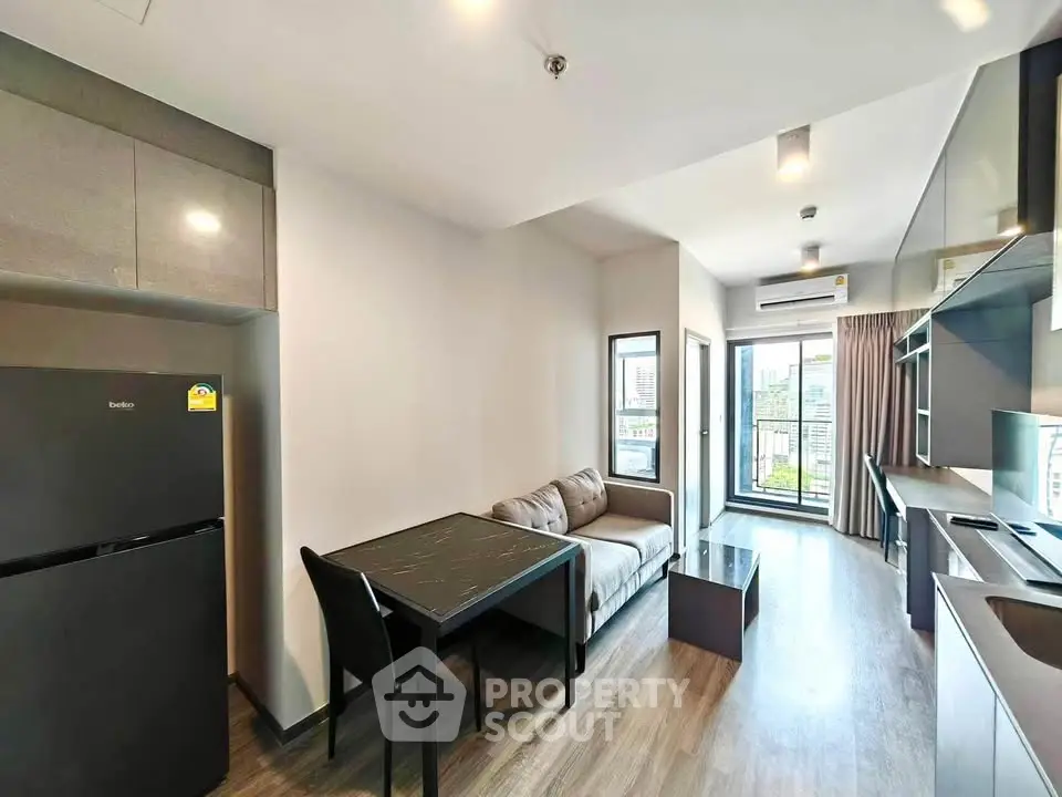 Modern apartment interior with sleek kitchen and cozy living area, featuring large windows and city view.