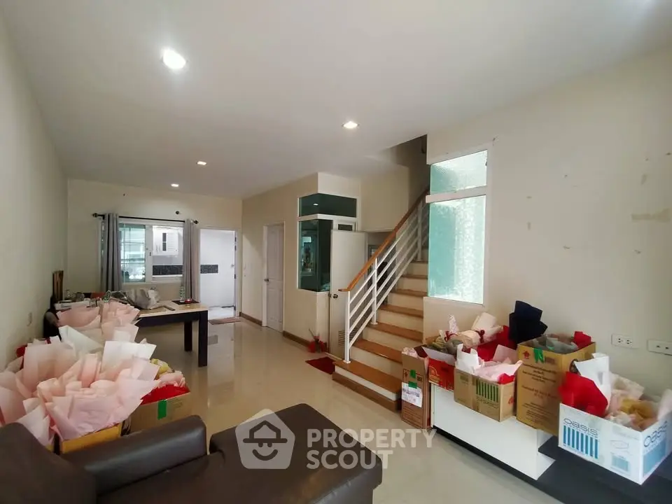 Spacious living room with modern staircase and ample natural light, perfect for family gatherings.