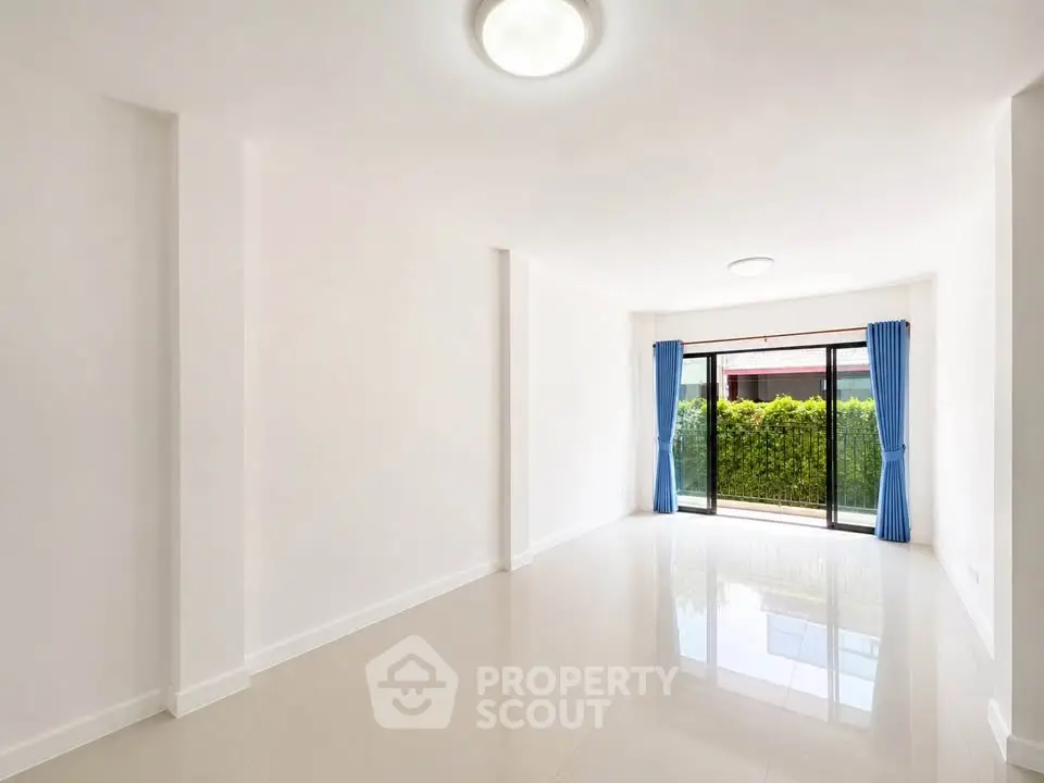 Spacious and bright living room with large windows and garden view, perfect for modern living.