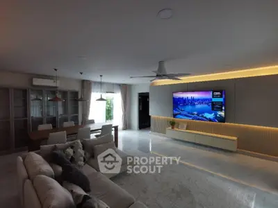 Spacious modern living room with elegant decor and large TV, perfect for entertainment.