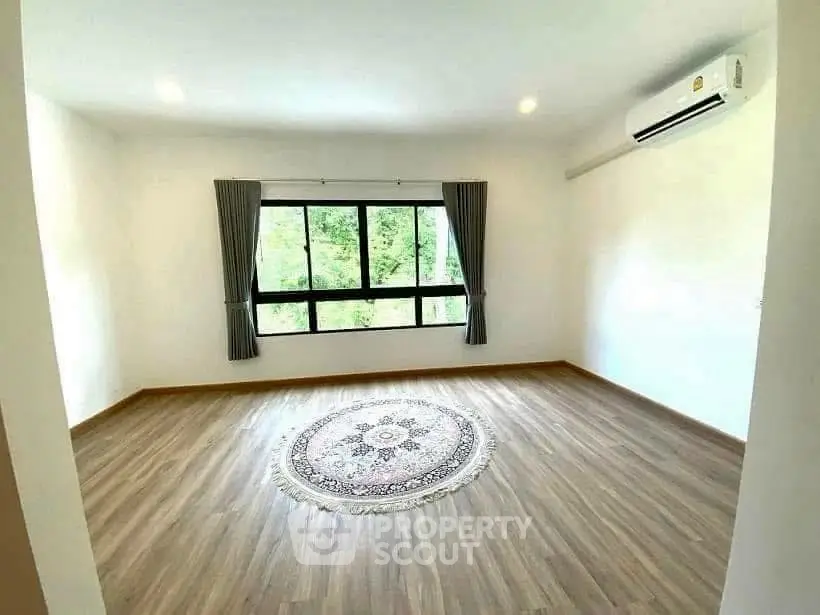 Spacious empty room with large window and air conditioning, perfect for customization.
