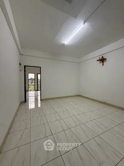 Spacious empty room with tiled flooring and bright lighting, ideal for customization.