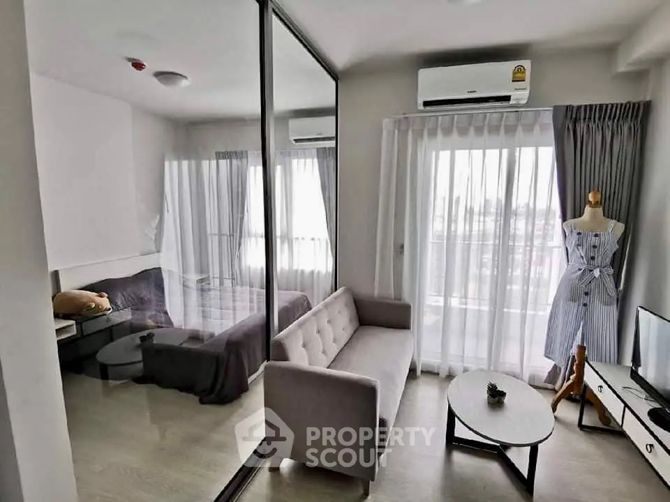 Modern studio apartment with glass partition, cozy living area, and ample natural light.