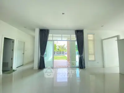 Spacious living room with large windows and garden view, perfect for modern living.