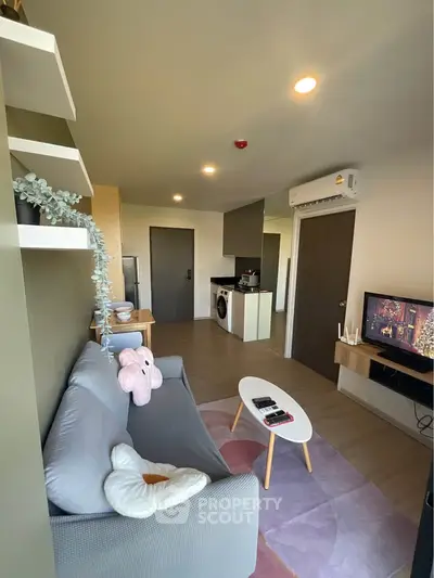 Modern living room with cozy sofa, TV, and open kitchen layout in stylish apartment.