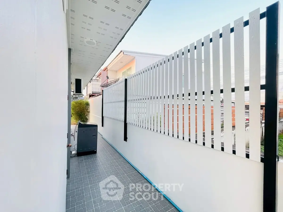 Modern exterior corridor with sleek fence and tiled flooring in a contemporary building.