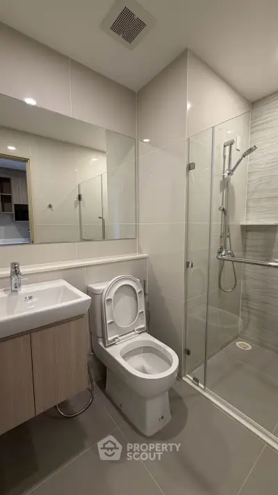 Modern bathroom with glass shower and sleek fixtures in contemporary apartment.