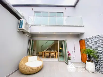 Modern open-air patio with stylish seating and dining area, featuring glass balcony and sleek design.