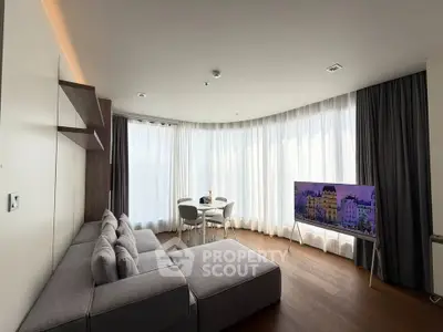 Modern living room with large windows, stylish gray sofa, and flat-screen TV, perfect for relaxation.