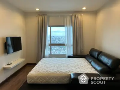 Modern bedroom with city view, featuring a sleek leather sofa and wall-mounted TV.