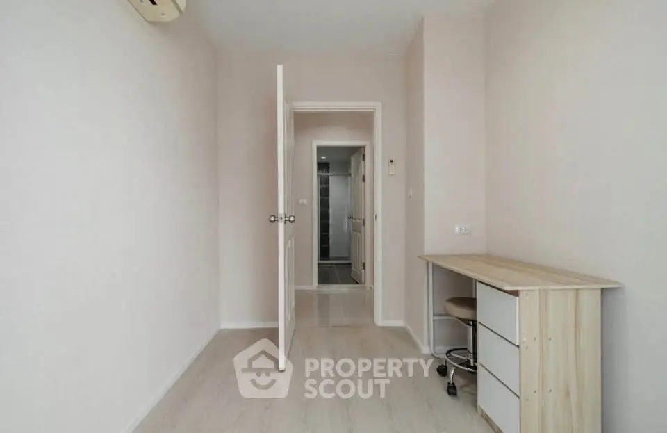 Minimalist study room with wooden desk and open door leading to hallway
