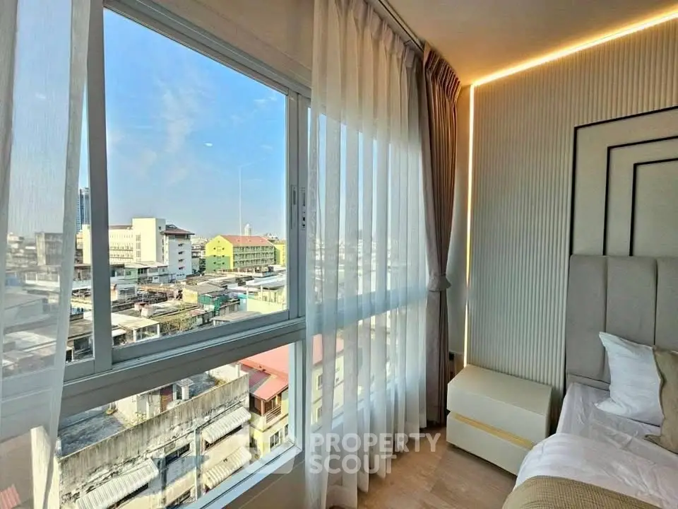 Bright bedroom with large window offering stunning city view and modern decor.