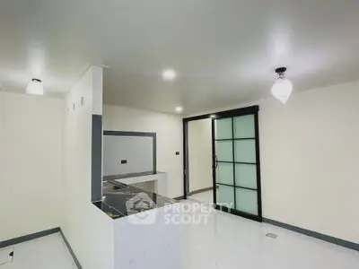 Modern open-layout kitchen with sleek marble countertops and sliding glass doors.