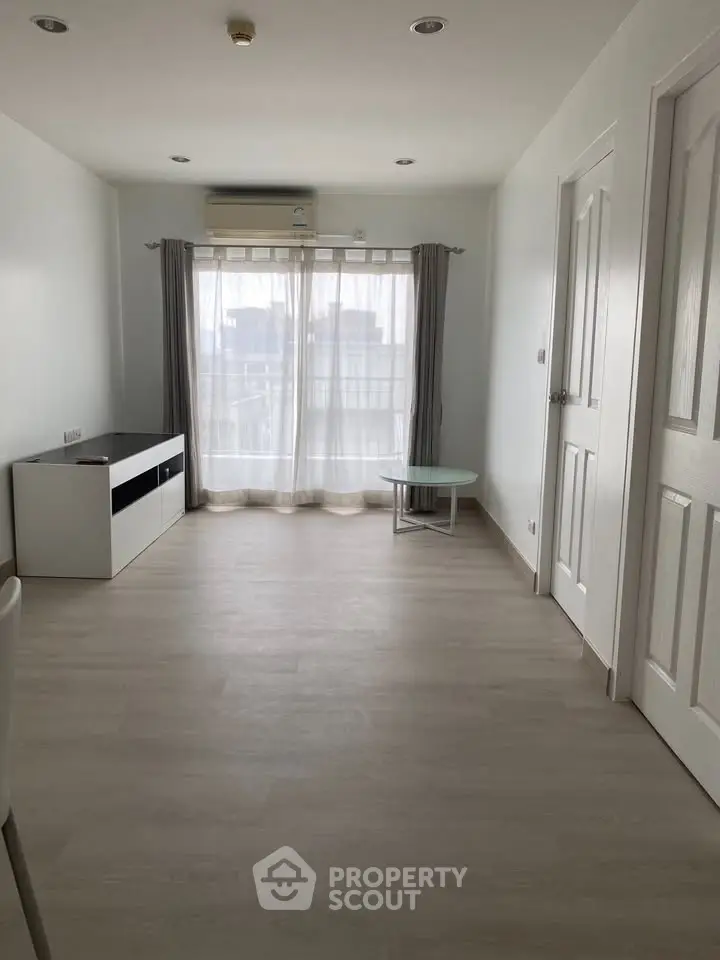 Spacious minimalist living room with large window and modern flooring