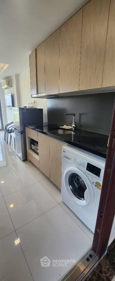 Modern kitchen with sleek cabinets and built-in washing machine in stylish apartment.