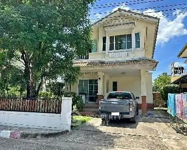 Charming two-story house with driveway and lush greenery in a serene neighborhood.