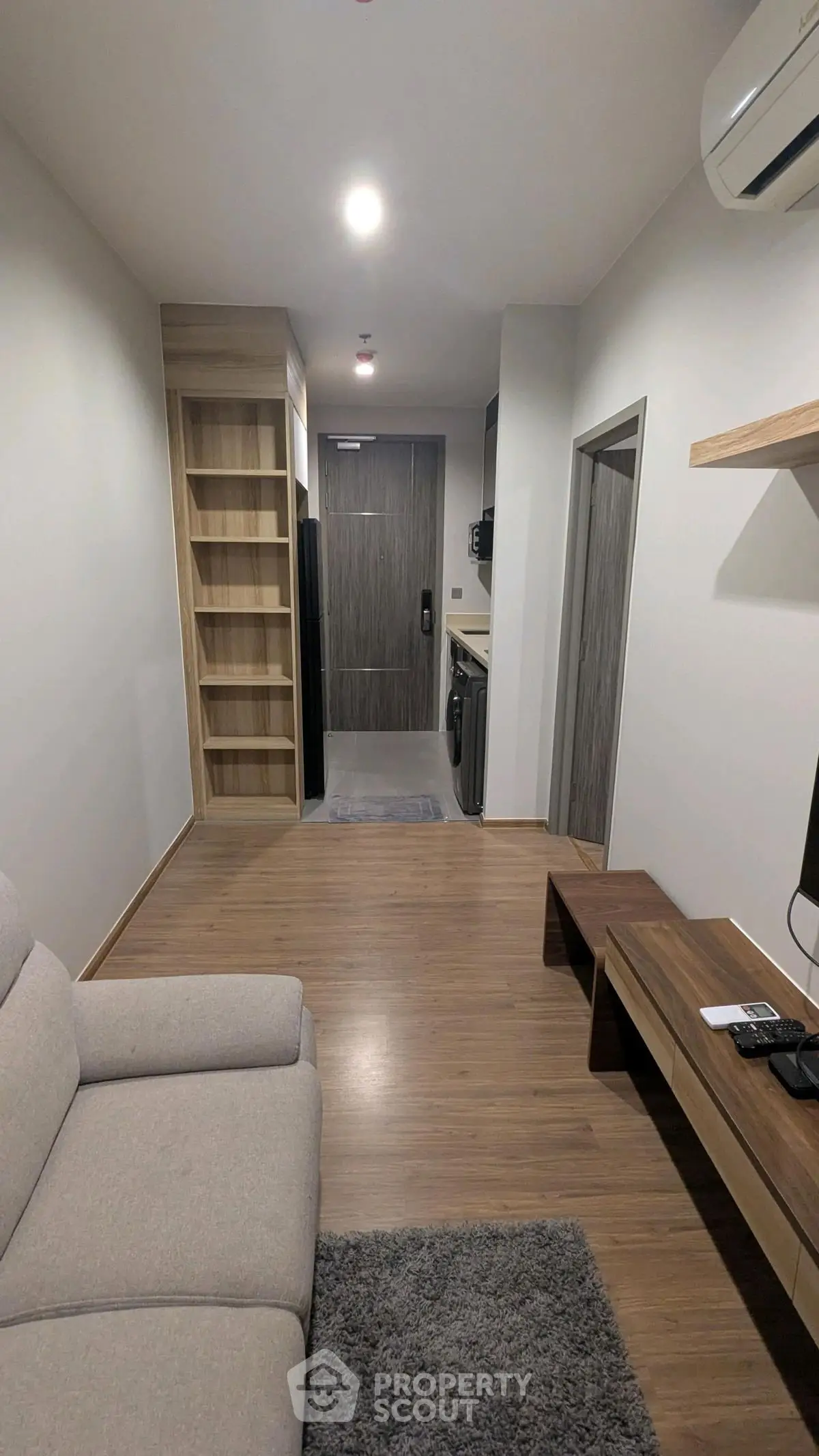 Modern living room with wooden flooring and built-in shelving in a cozy apartment.