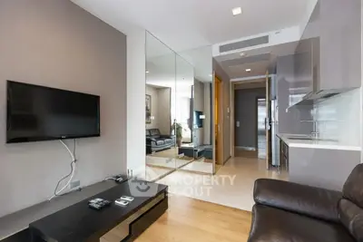 Modern living room with sleek design and mirrored wall, featuring a flat-screen TV and leather sofa.