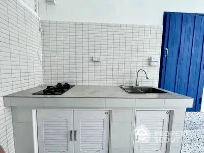 Sleek modern kitchen with white subway tiles, grey countertops, and a vibrant blue door, featuring a gas stove and ample cabinet space.