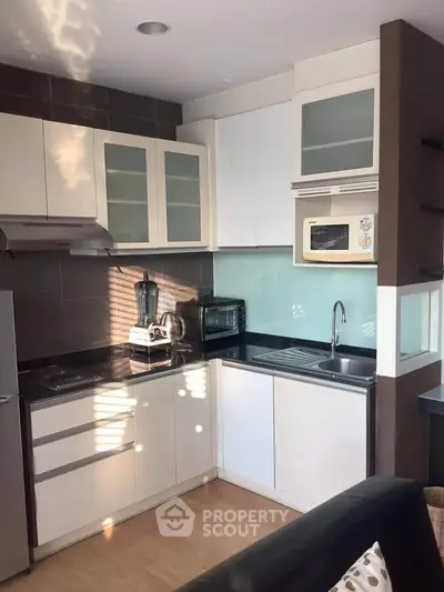 Modern kitchen with sleek cabinetry and built-in appliances, featuring a microwave and blender.
