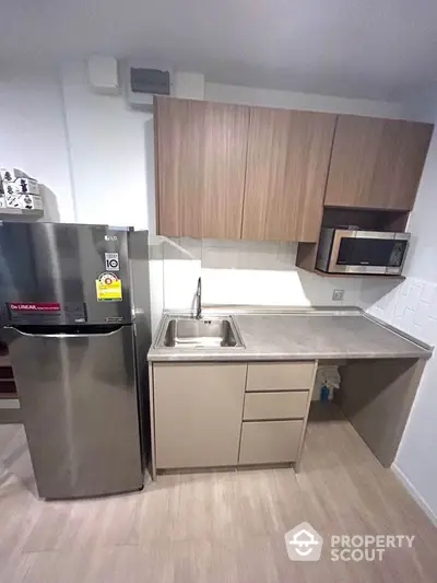 Modern compact kitchen with stainless steel appliances and wooden cabinets