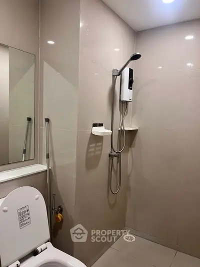 Modern bathroom with sleek shower and toilet in minimalist design.