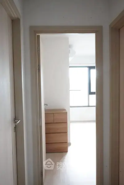 Bright hallway leading to a minimalist bedroom with natural light and modern decor.
