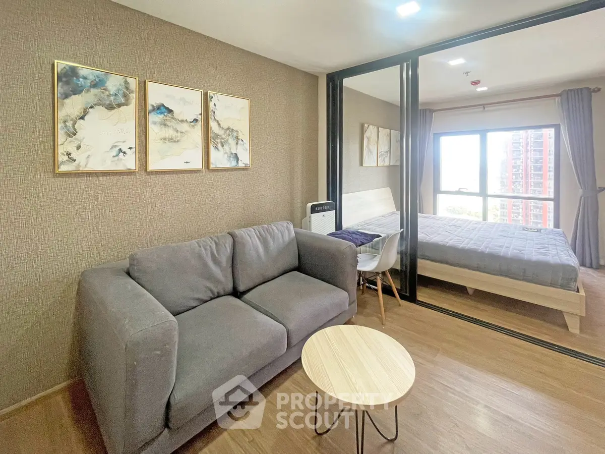 Modern apartment interior with cozy living room and stylish bedroom separated by glass partition.